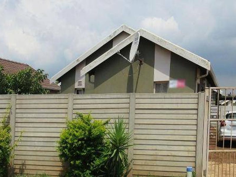 Front view of a residential house featuring a precast concrete boundary wall, metal gate, and tiled roof structure.