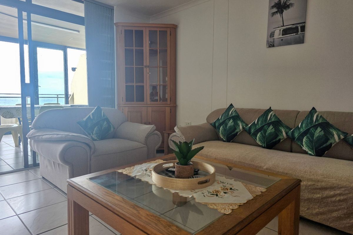A living room featuring tiled flooring and a sliding glass door leading to a balcony, with a built-in corner cabinet.
