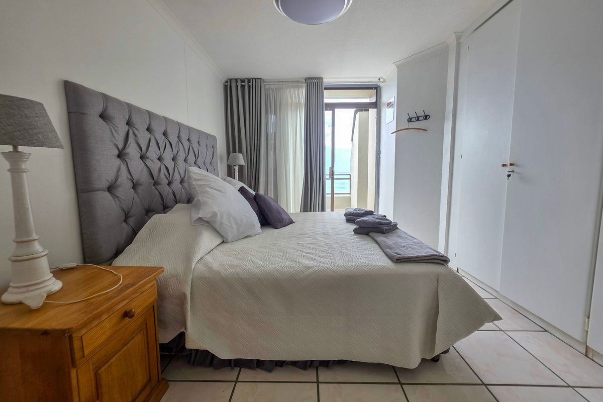 A well-maintained bedroom featuring tiled flooring, built-in cupboards, and a sliding door providing direct access to a private balcony.
