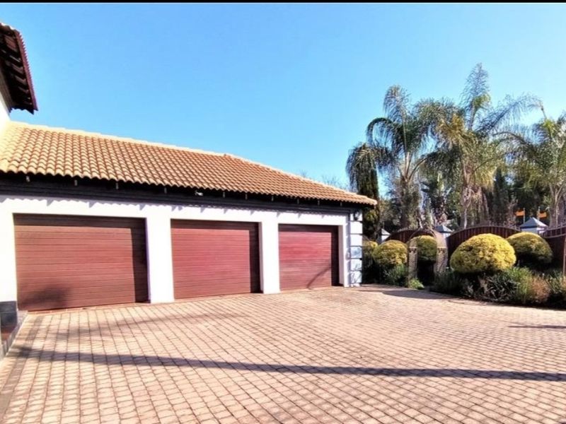 A well-maintained triple garage featuring wooden-style sectional doors and a spacious paved driveway area.