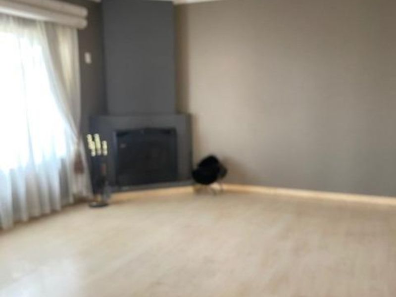 Spacious living room featuring light-toned laminate flooring, a modern corner fireplace, and neutral wall finishes, offering a bright and versatile open living space.