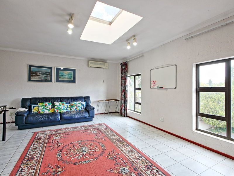 Spacious living room featuring tiled flooring, a large skylight for natural light, and a wall-mounted air conditioning unit.