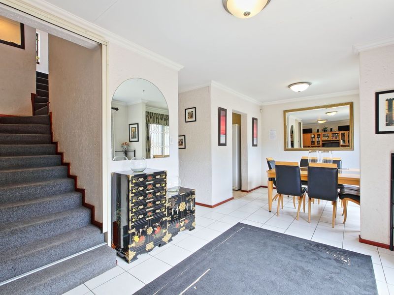 Open plan living and dining area featuring tiled flooring, a staircase leading to the upper level, and neutral wall finishes.