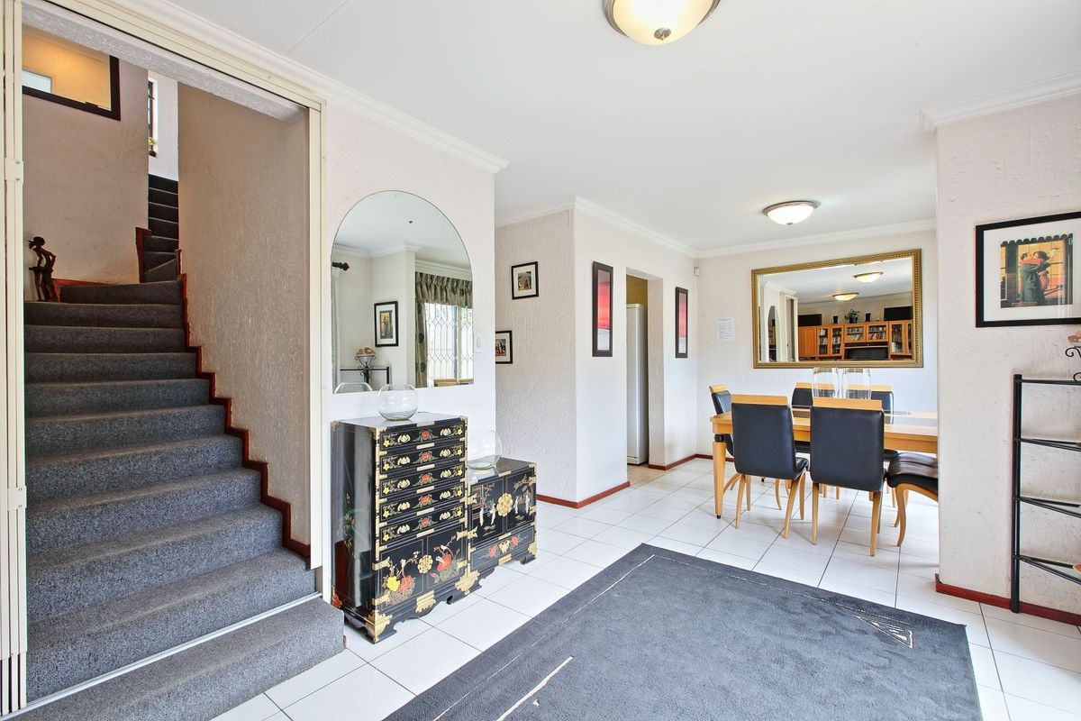 Open plan living and dining area featuring tiled flooring, a staircase leading to the upper level, and neutral wall finishes.