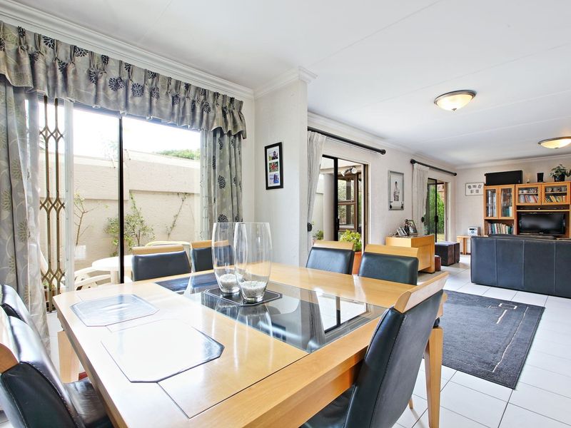 Spacious open-plan living and dining area featuring tiled floors, large sliding doors providing natural light, and direct access to the outdoor patio area.
