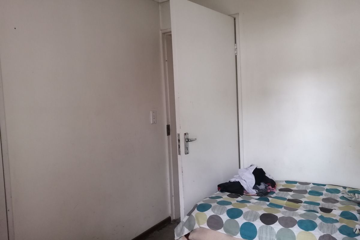 A simple bedroom interior featuring plain walls and a standard door, requiring cosmetic updates to improve the overall aesthetic and condition.