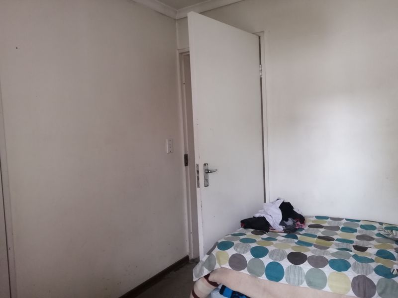 A simple bedroom interior featuring plain walls and a standard door, requiring cosmetic updates to improve the overall aesthetic and condition.