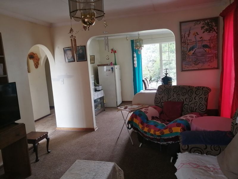 Open plan living area featuring arched doorways and carpeted flooring, connecting to a secondary space with natural light.