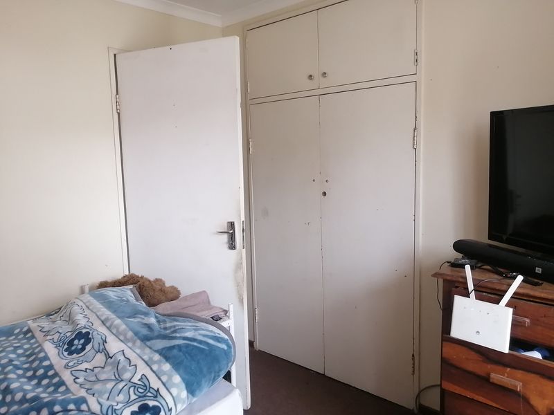 A bedroom featuring built-in cupboards and a standard internal door, showing signs of wear and tear on the door frame.