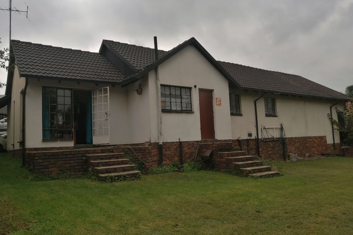 Rear view of a single-story house featuring a tiled roof, brick base, and multiple entry points with external stairs leading to the garden.