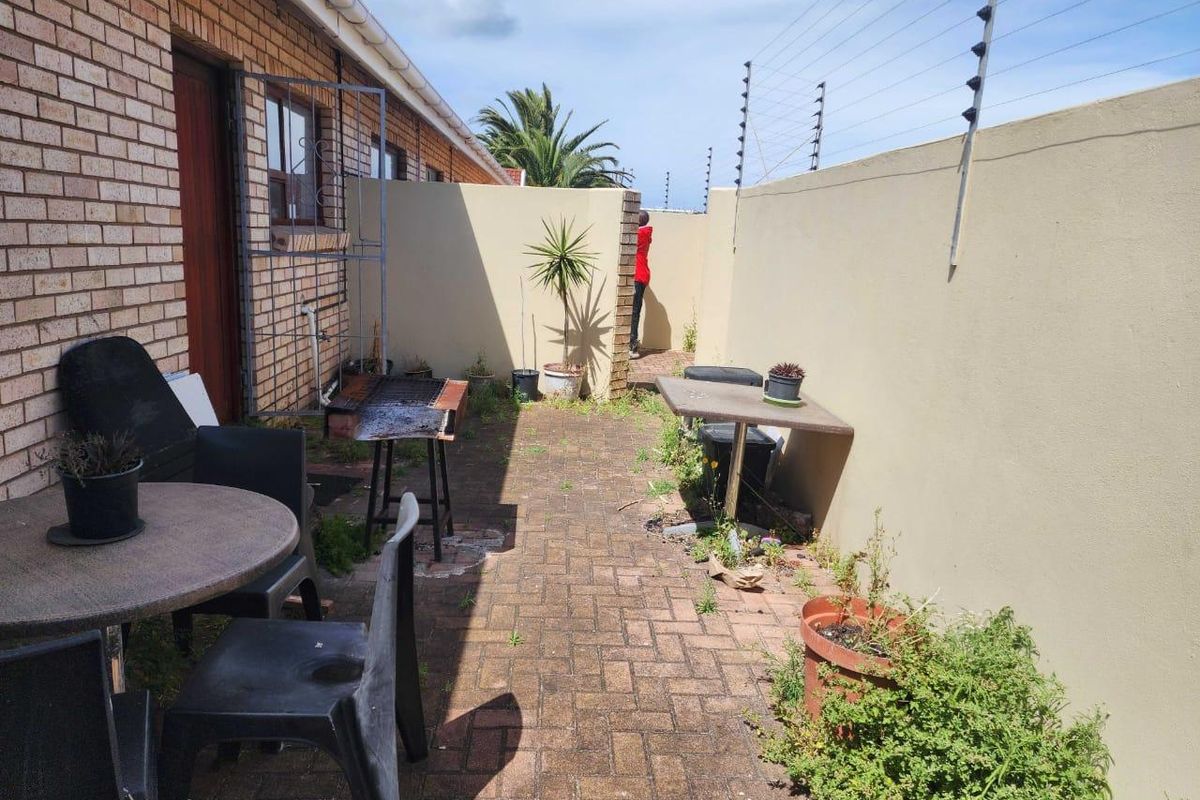 A private rear courtyard featuring brick paving, enclosed by high perimeter walls with integrated electric fencing.