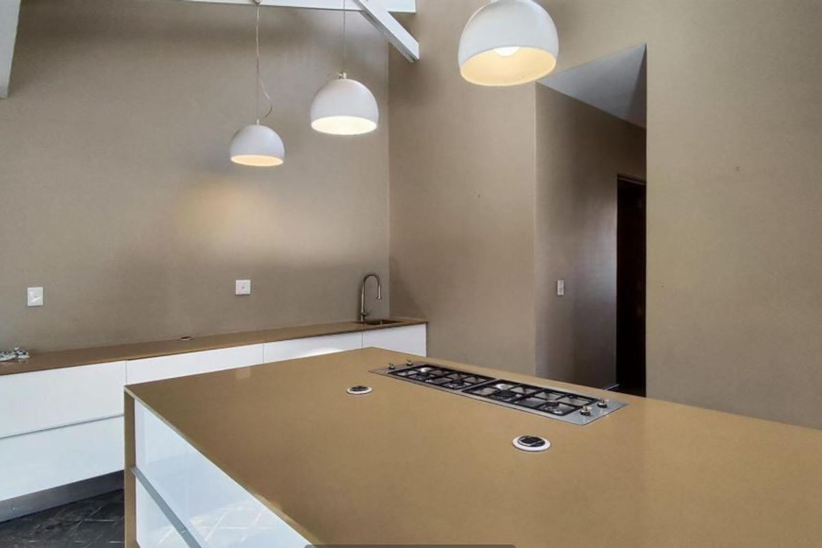Modern kitchen featuring a large island with a built-in gas cooktop, stone countertops, sleek cabinetry, and contemporary pendant lighting.