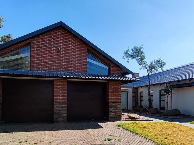 Front view of a modern house featuring a double garage, brick and stone facade, and a paved driveway.