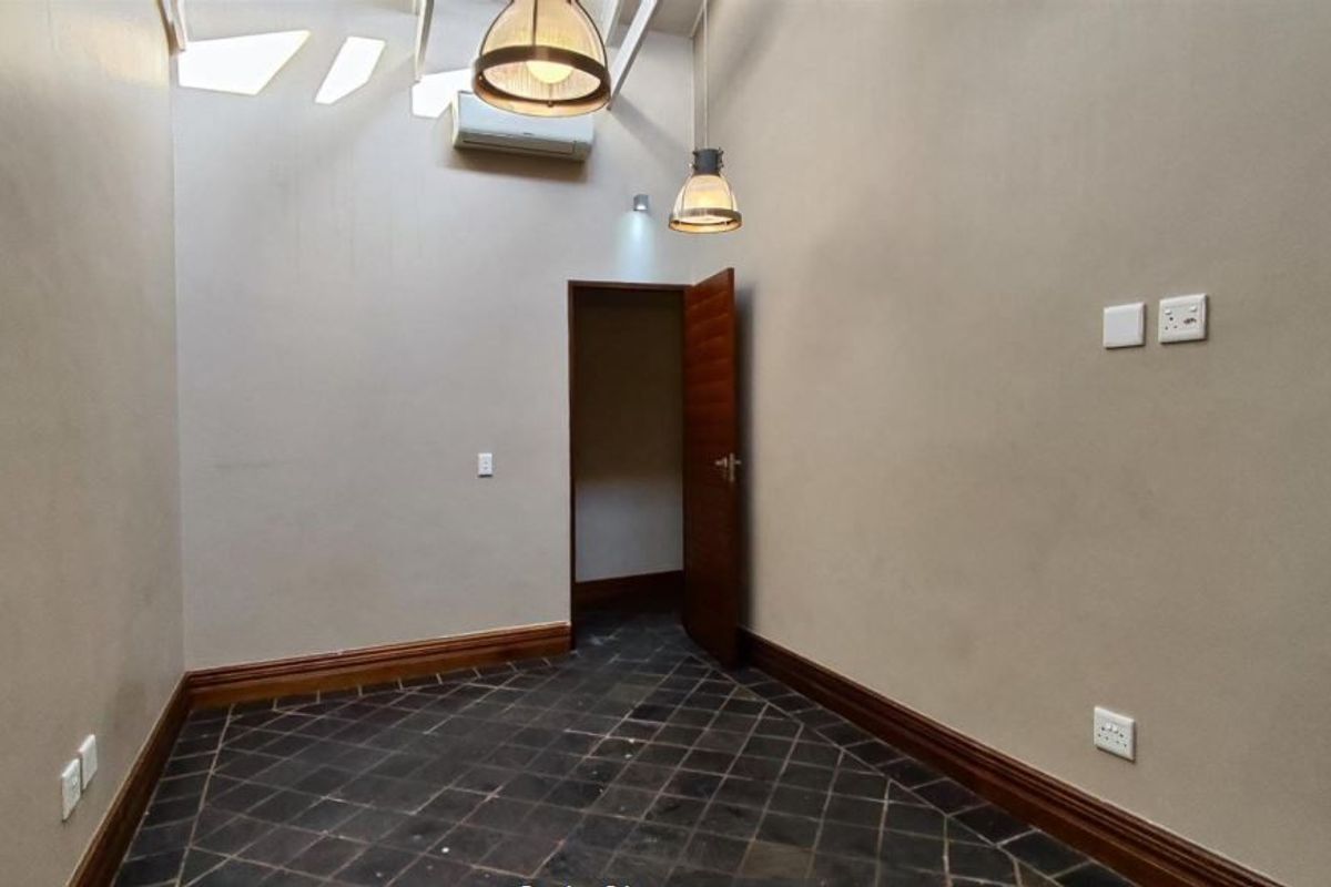 An empty bedroom featuring slate tile flooring, timber skirting boards, a split-system air conditioner, and pendant lighting.