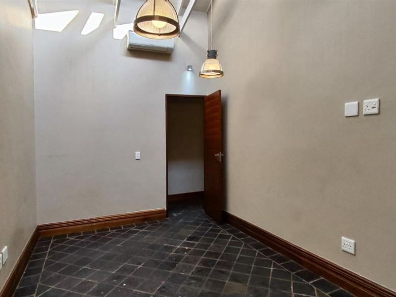 An empty bedroom featuring slate tile flooring, timber skirting boards, a split-system air conditioner, and pendant lighting.