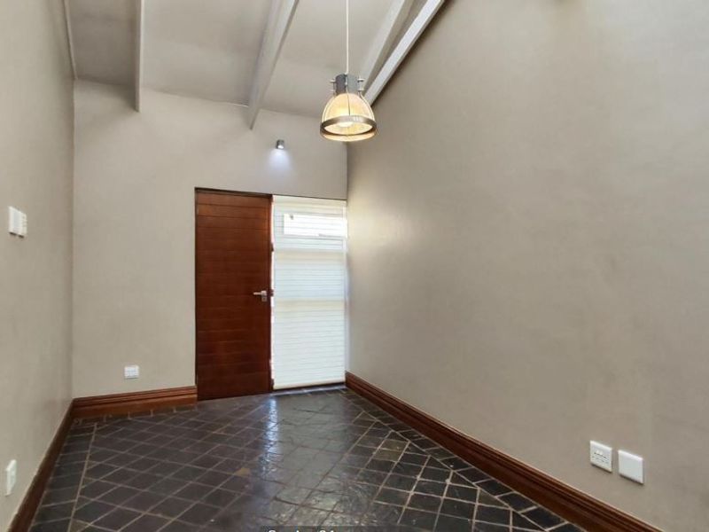 An empty living space featuring high exposed beam ceilings, dark slate tile flooring, and a solid timber door.