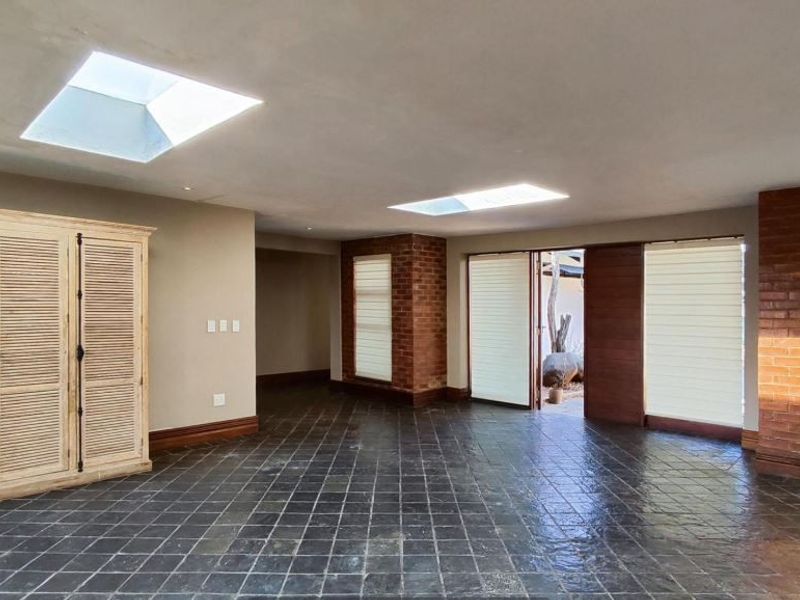 Spacious living area featuring slate tile flooring, exposed brick accents, and dual skylights, providing a bright and open atmosphere with direct outdoor access.