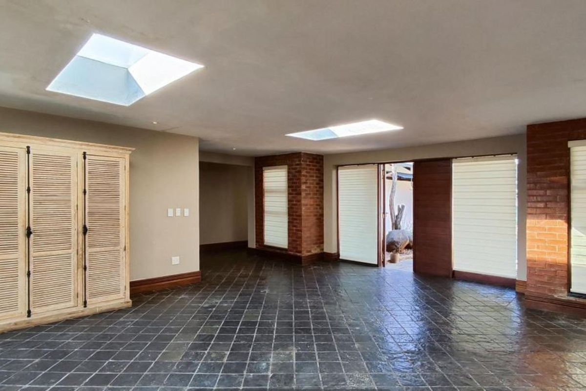 Spacious living area featuring slate tile flooring, exposed brick accents, and dual skylights, providing a bright and open atmosphere with direct outdoor access.