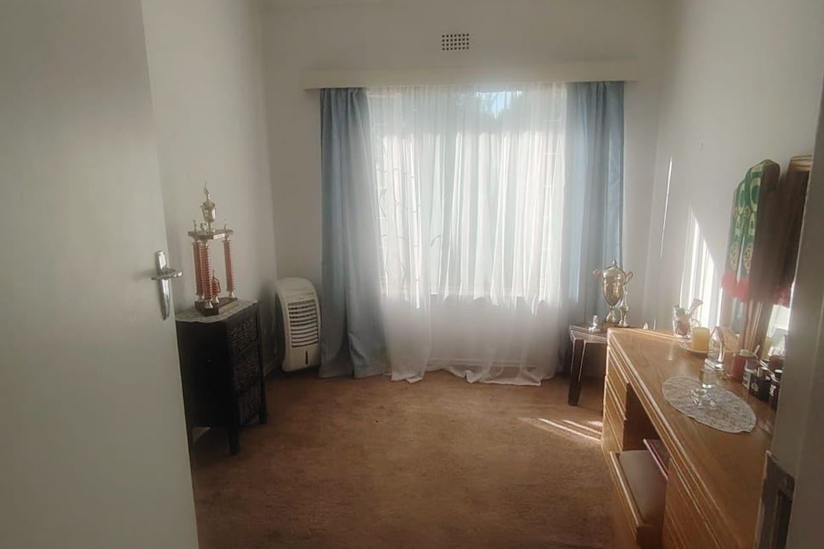 A standard bedroom featuring carpeted flooring, a central ceiling light, and window treatments, offering a functional space ready for personalization.