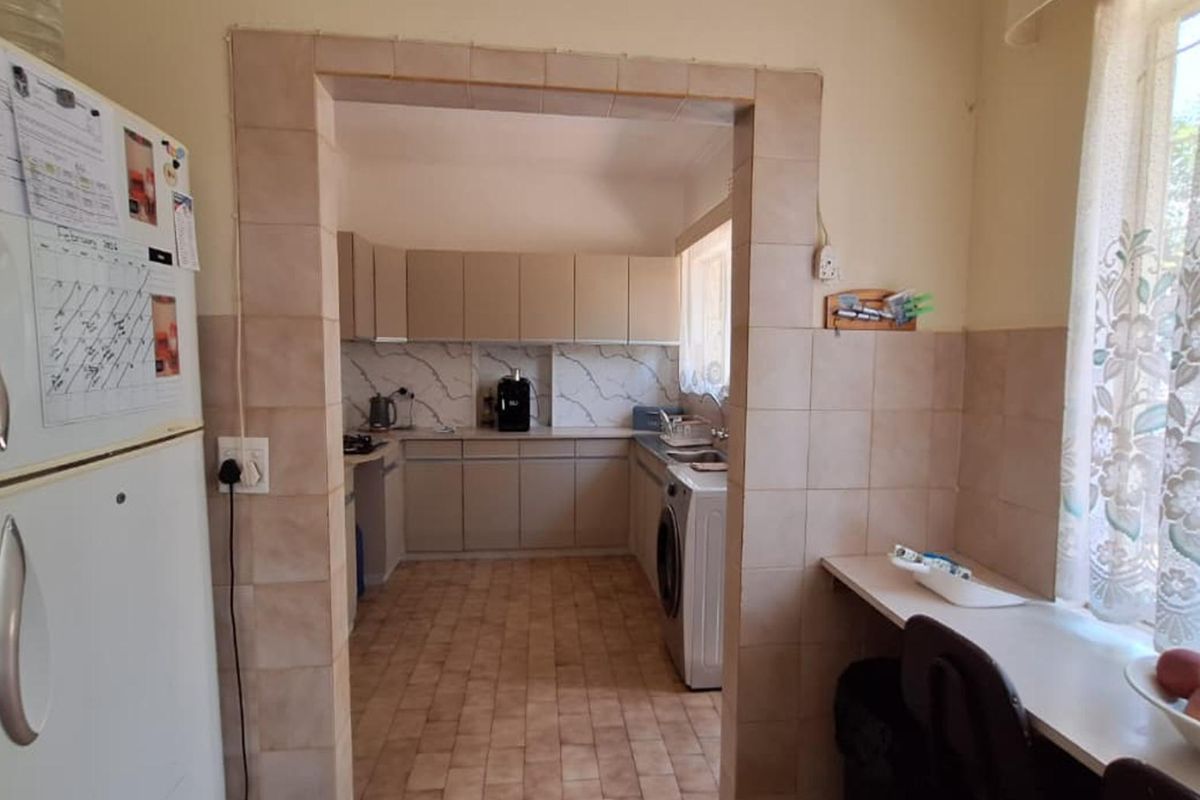 A functional kitchen featuring tiled flooring, ample built-in cabinetry, and a tiled splashback, providing a practical workspace with a connected breakfast nook area.