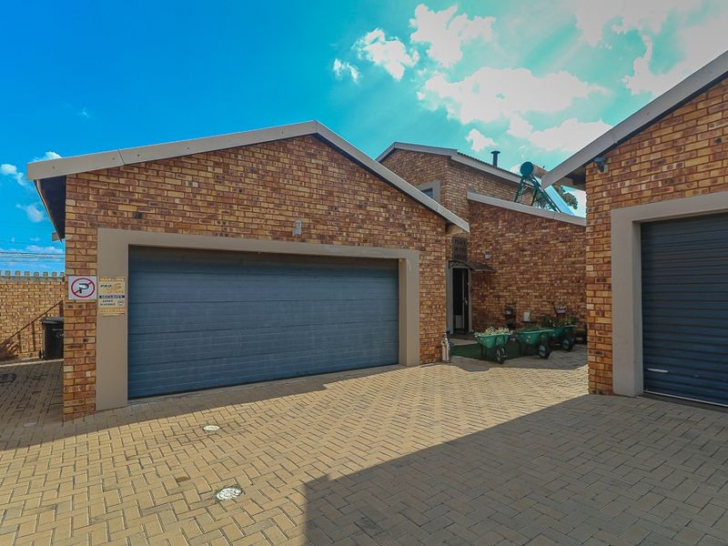 Exterior view of the property featuring a double garage with paved driveway and face-brick facade.