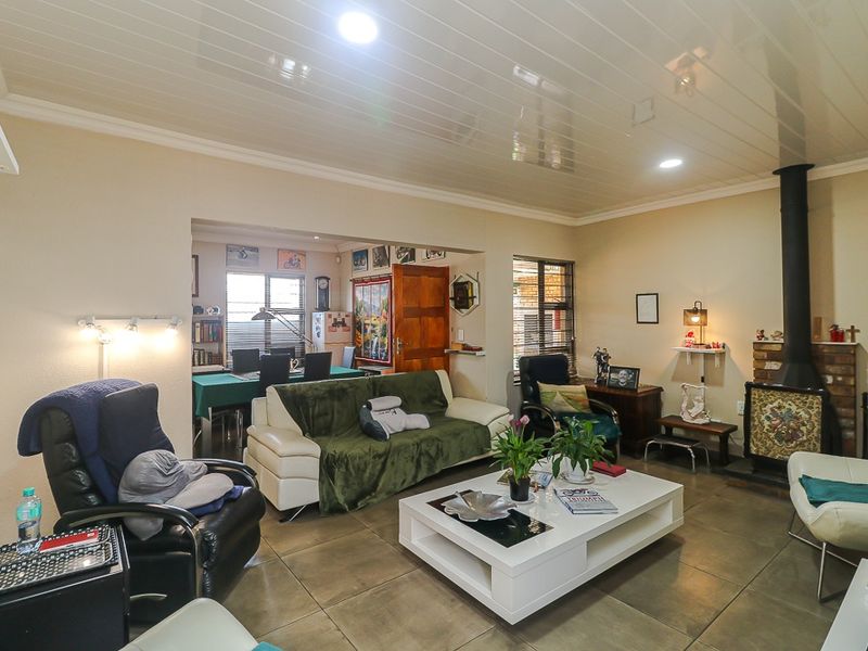 Open plan living area featuring a wood-burning fireplace, tiled flooring, and a glossy panelled ceiling, seamlessly connecting to the adjacent dining space.