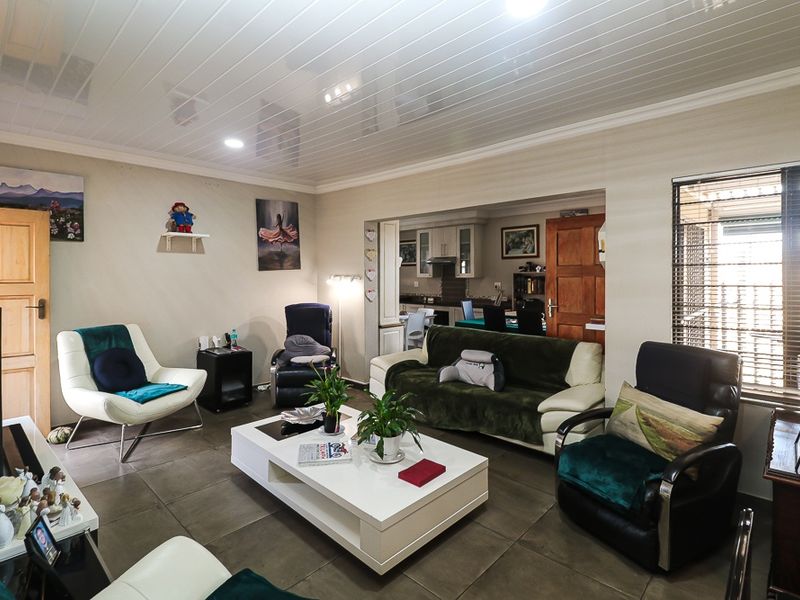 Spacious open-plan living area featuring tiled flooring, a glossy panelled ceiling, and a seamless transition into the adjacent kitchen and dining space.