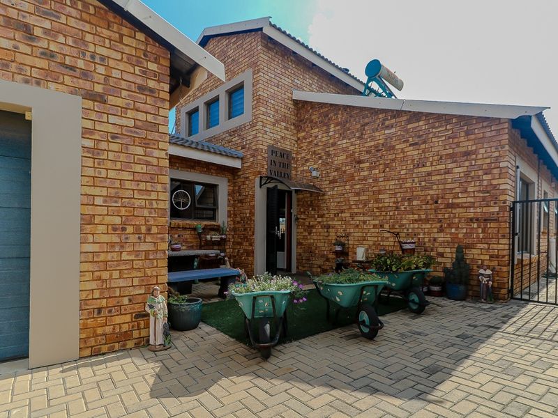 A view of the exterior entrance area featuring face brick facade, paved courtyard, and solar water heating system.