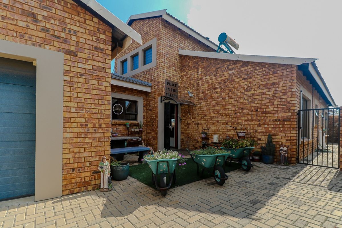 A view of the exterior entrance area featuring face brick facade, paved courtyard, and solar water heating system.