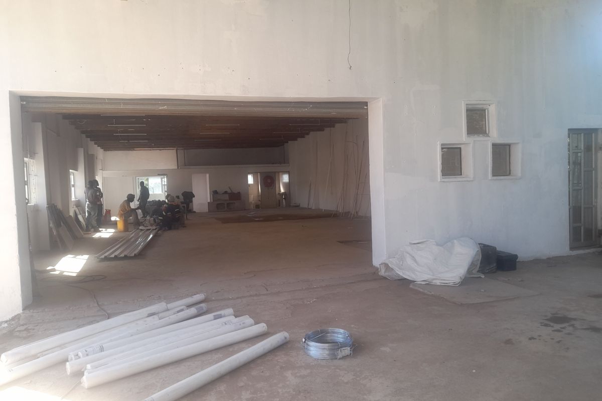A large, open-plan industrial utility space featuring exposed timber ceiling beams, concrete flooring, and unfinished wall surfaces, suitable for workshop or storage use.