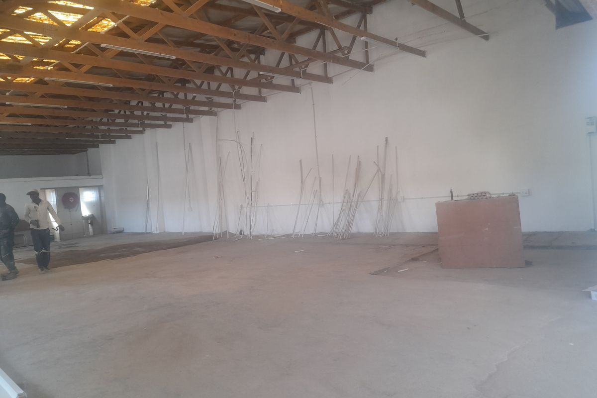 Spacious industrial utility area featuring exposed timber roof trusses, concrete flooring, and basic lighting, suitable for warehouse or workshop use.