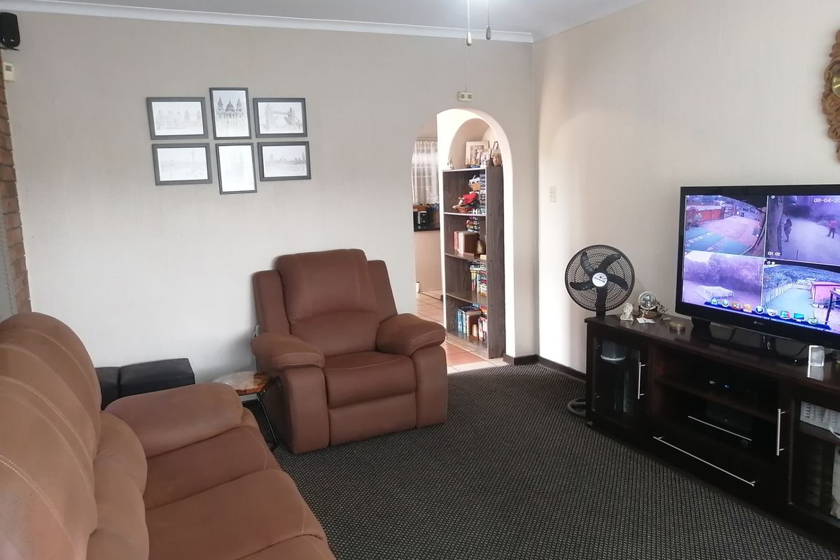 A comfortable living room featuring carpeted flooring, an arched doorway leading to an adjacent space, and neutral wall finishes.