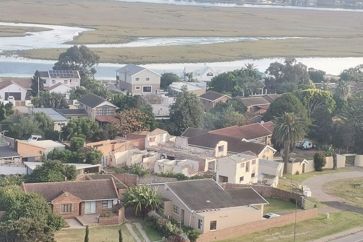 An aerial view of a residential neighborhood situated near a wetland area, showcasing the surrounding landscape and local housing density.