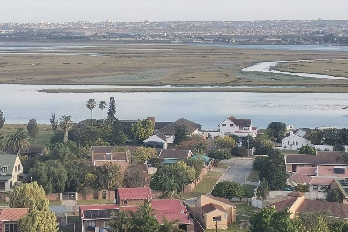 An elevated aerial view overlooking a residential neighborhood with a scenic lagoon and coastal landscape in the background.