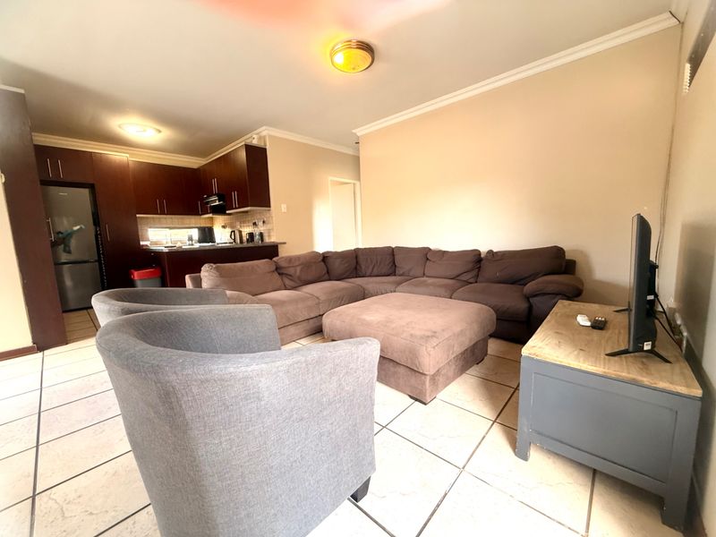 Open plan living area featuring tiled flooring and a kitchen with dark wood cabinetry, providing a functional and connected space for daily living.