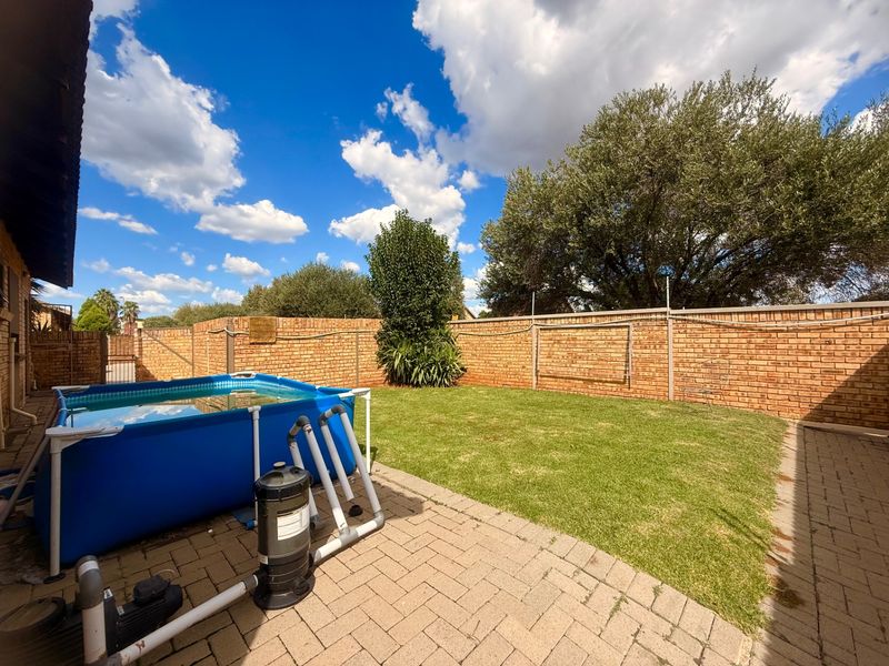 A private rear garden featuring a paved patio area, a well-maintained lawn, and a high brick boundary wall for added privacy.