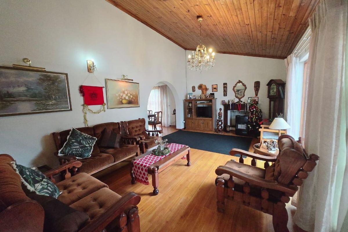 Spacious living room featuring high timber-clad ceilings, hardwood flooring, a traditional fireplace, and an elegant archway leading to the dining area.
