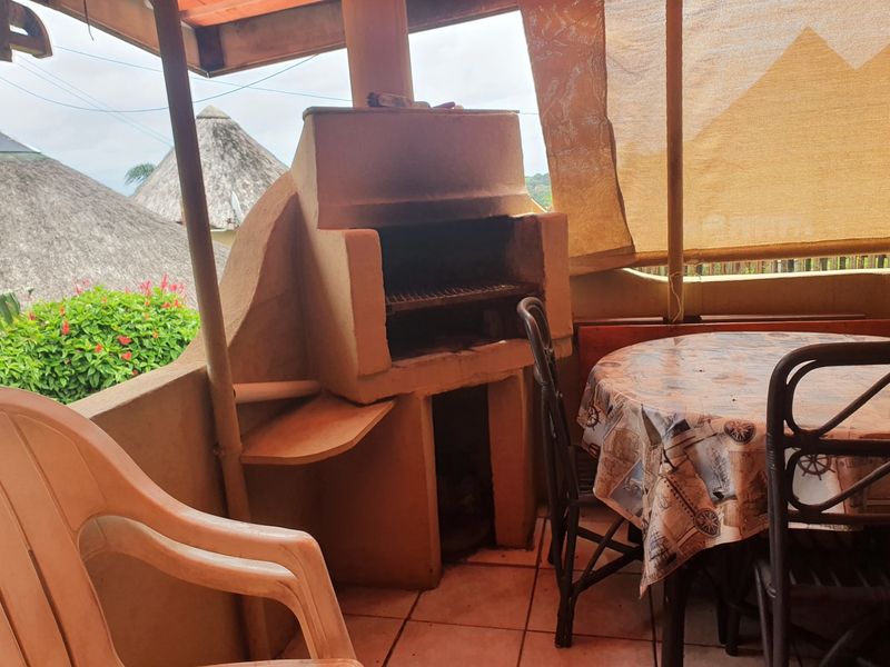 Covered patio area featuring a built-in braai and tiled flooring, offering a functional outdoor entertainment space.