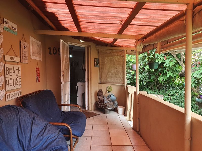 A covered patio area featuring tiled flooring and a low masonry wall, providing a functional outdoor space with direct access to the home.