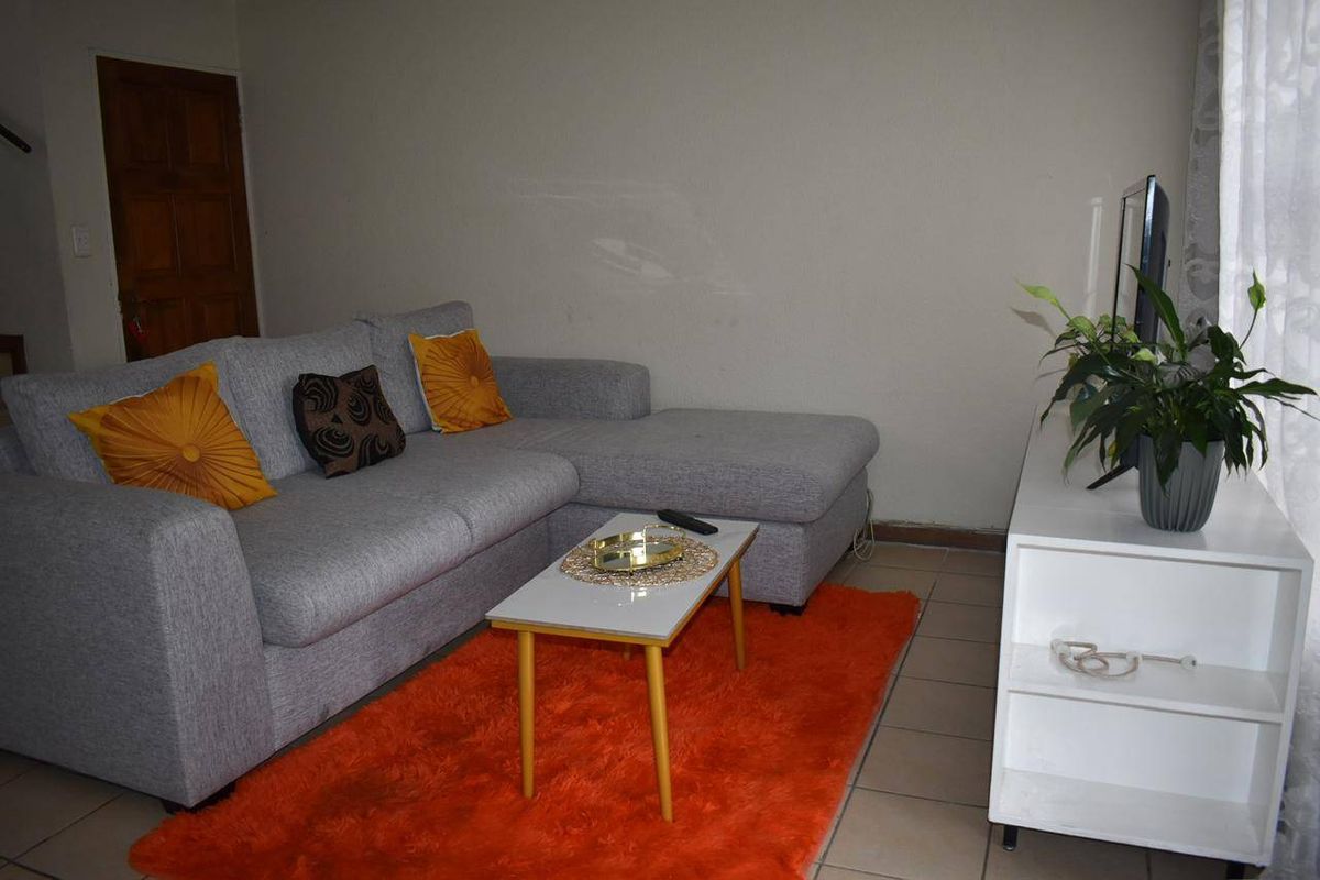 A functional living room featuring tiled flooring and a standard wooden door, providing a comfortable and practical space for relaxation.