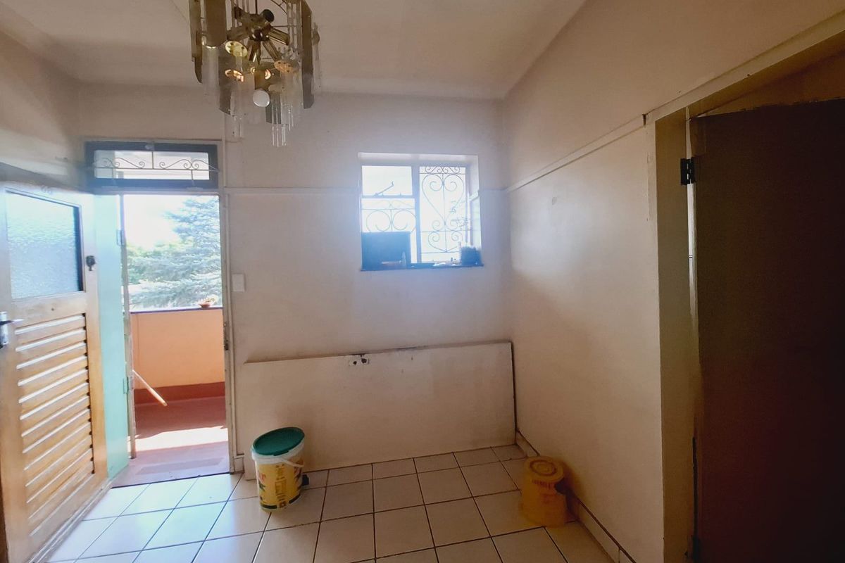 An empty living area featuring tiled flooring, a decorative ceiling light, and direct access to an outdoor balcony through a security door.
