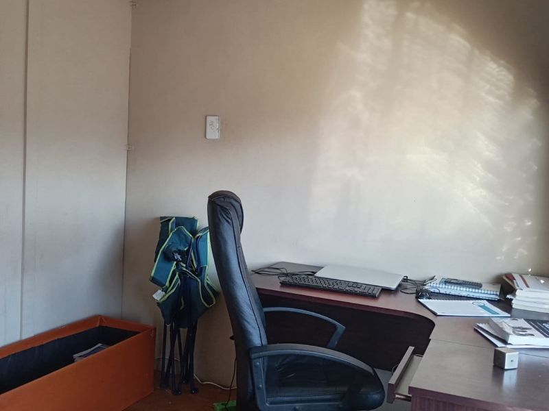 A small home office space featuring hardwood flooring and a wall-mounted light fixture, suitable for a dedicated workspace or study area.