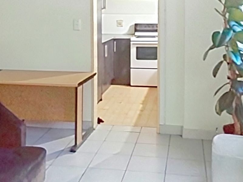 A view from the living area looking into a kitchen featuring tiled flooring and built-in cabinetry with a freestanding stove.