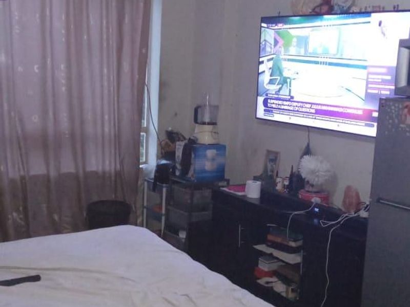 A bedroom featuring a ceiling fan and window with curtains, providing a functional living space.