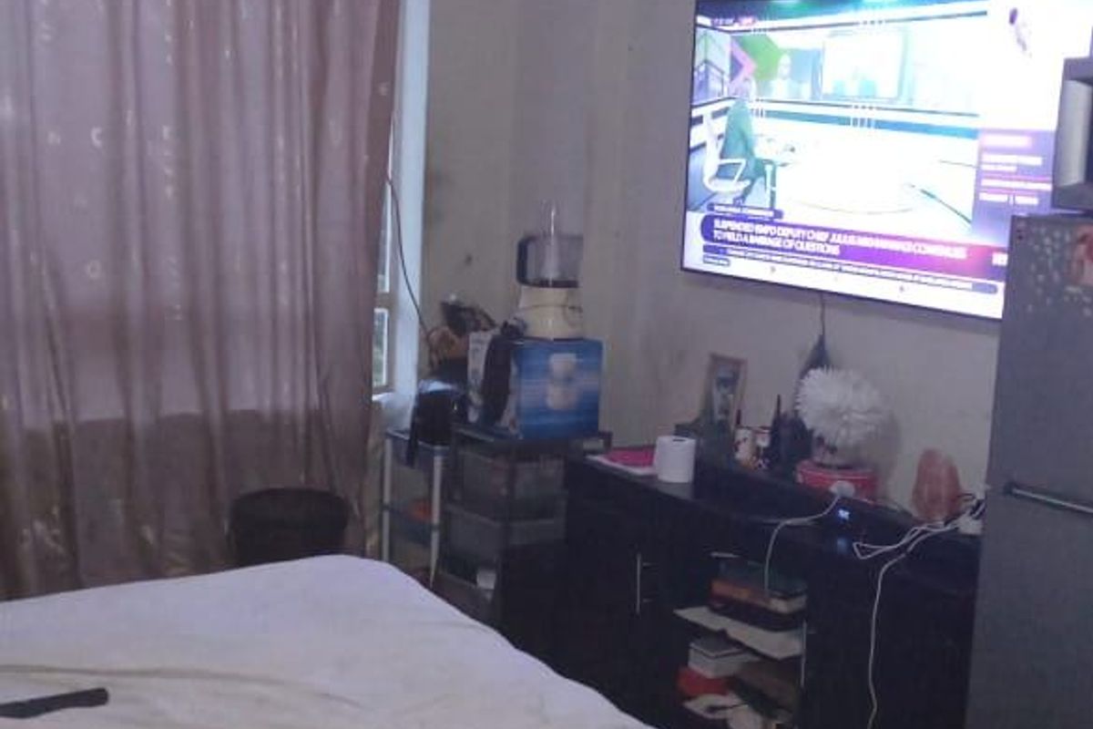 A bedroom featuring a ceiling fan and window with curtains, providing a functional living space.