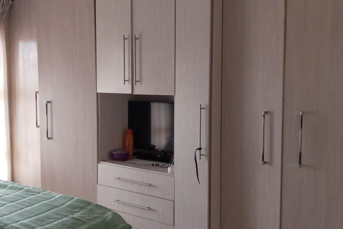 A bedroom featuring extensive built-in light wood cabinetry with integrated storage and shelving, providing ample space for organization.
