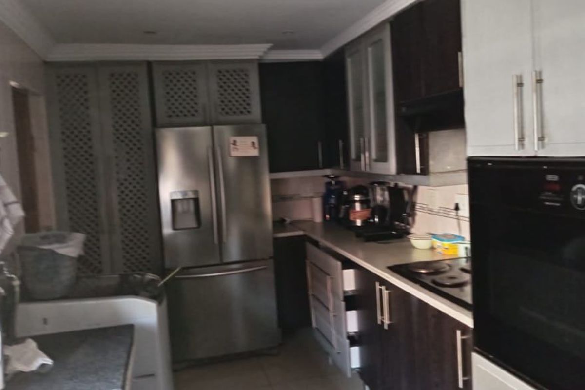 A functional kitchen featuring dark cabinetry, built-in oven, hob, and integrated storage space with a tiled floor.