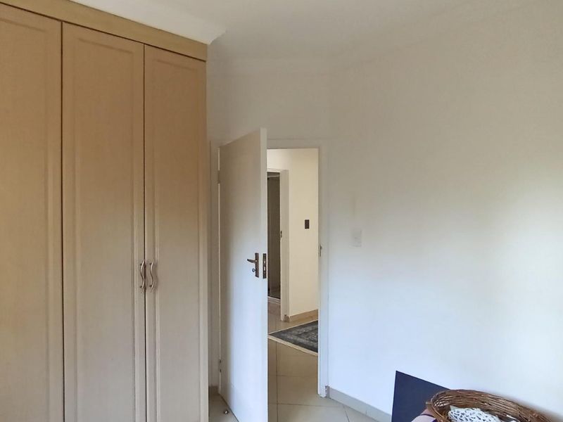 A clean, empty bedroom featuring neutral tiled flooring and ample built-in cupboard storage, offering a blank canvas for personalization.