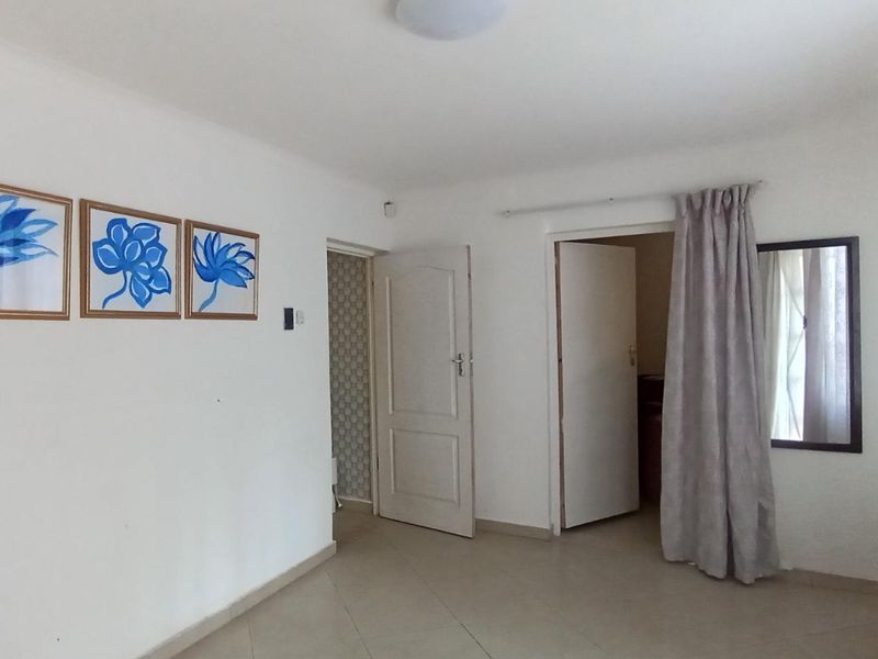 A bright, empty living area featuring neutral tiled flooring and multiple internal doorways, providing a versatile space ready for personalization.