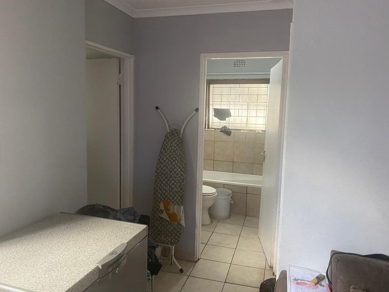 A functional hallway area providing access to a bathroom with tiled finishes and a window.